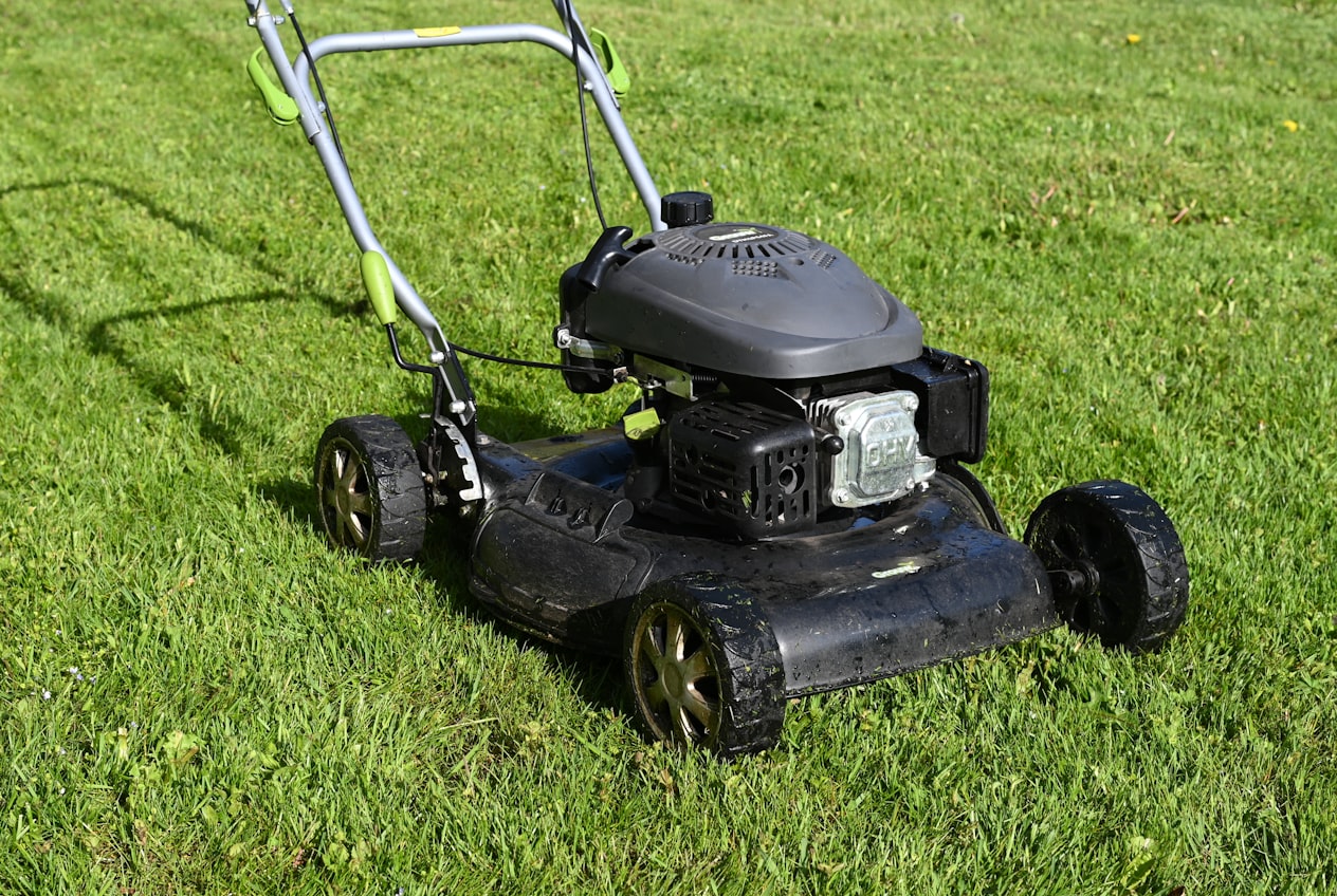 A mower cutting a freshly striped, healthy green lawn